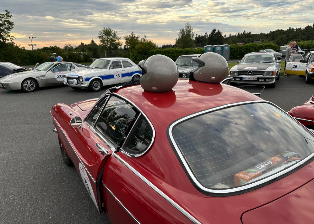 Two helmets on the roof of a red Volvo 1800E